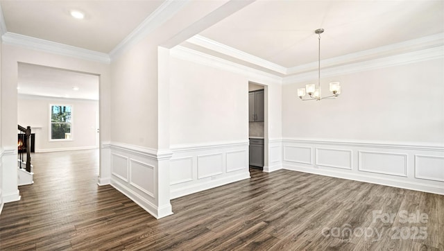 spare room with a notable chandelier, ornamental molding, and dark hardwood / wood-style floors