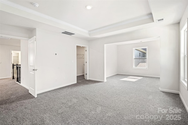 empty room featuring crown molding, a tray ceiling, and carpet flooring