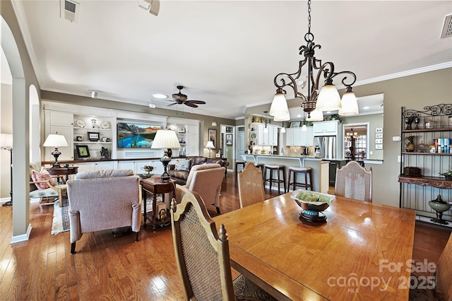 dining area with hardwood / wood-style flooring, crown molding, and ceiling fan with notable chandelier