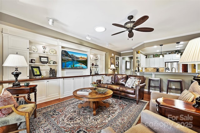 living room with hardwood / wood-style flooring, crown molding, and ceiling fan