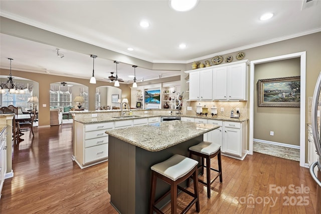 kitchen with hanging light fixtures, a kitchen breakfast bar, white cabinets, a kitchen island, and kitchen peninsula