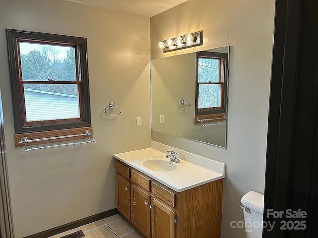 bathroom with baseboards, vanity, tile patterned flooring, and toilet