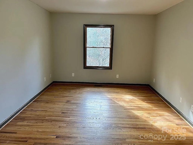 unfurnished room featuring baseboards and wood finished floors
