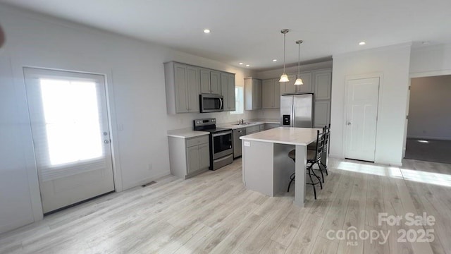 kitchen with appliances with stainless steel finishes, gray cabinets, and a kitchen breakfast bar