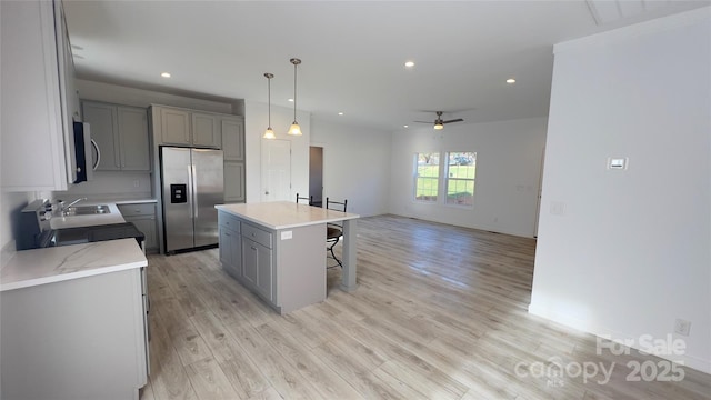 kitchen with light wood-type flooring, gray cabinets, stainless steel appliances, and a kitchen breakfast bar