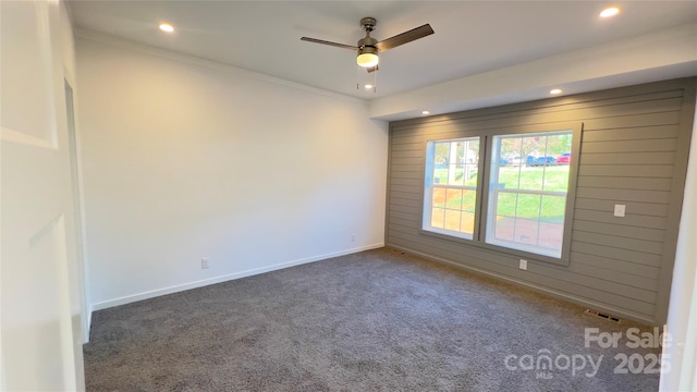 carpeted spare room with recessed lighting, visible vents, a ceiling fan, wooden walls, and baseboards