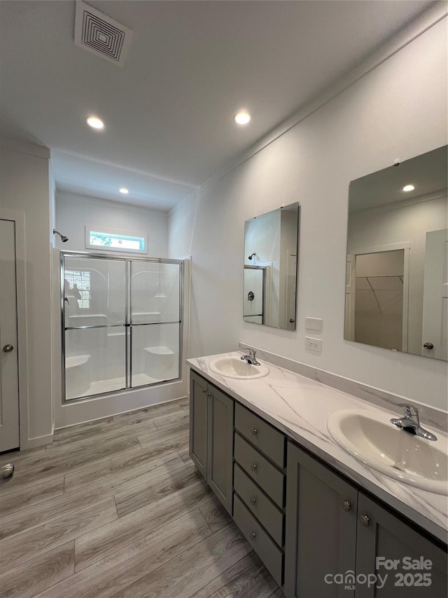 full bath featuring wood finished floors, an enclosed shower, a sink, and visible vents