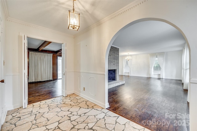 interior space with beamed ceiling, ornamental molding, hardwood / wood-style floors, and a brick fireplace