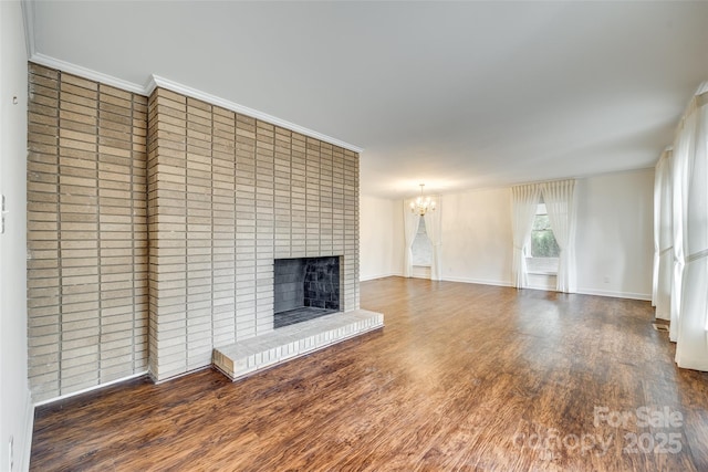 unfurnished living room with ornamental molding, dark hardwood / wood-style floors, an inviting chandelier, and a fireplace