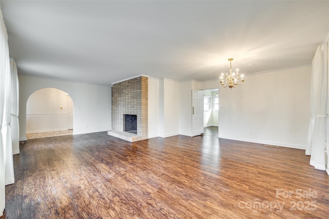 unfurnished living room with an inviting chandelier, crown molding, a fireplace, and hardwood / wood-style flooring