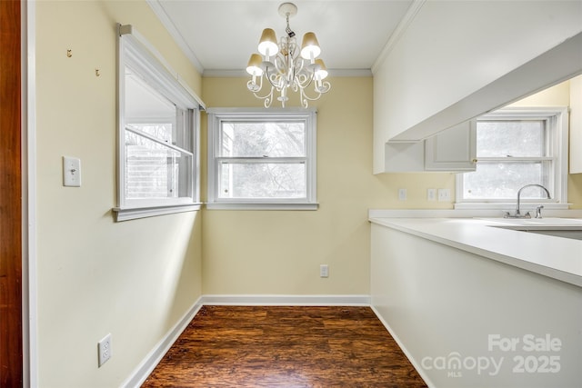 unfurnished dining area with dark wood-type flooring, ornamental molding, a chandelier, and sink