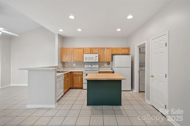 kitchen featuring tasteful backsplash, light tile patterned floors, white appliances, and a kitchen island