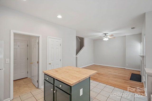 kitchen featuring light tile patterned floors, green cabinetry, ceiling fan, and a kitchen island