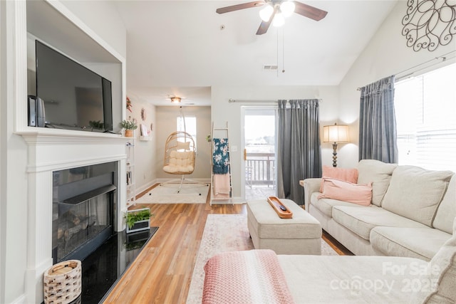 living room with ceiling fan, light hardwood / wood-style floors, and lofted ceiling