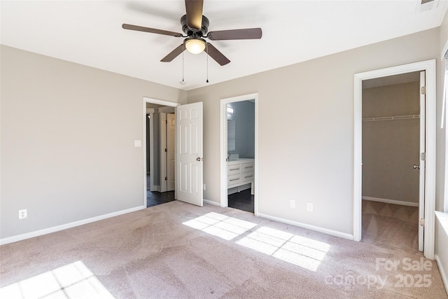 unfurnished bedroom featuring a spacious closet, ensuite bath, carpet floors, a closet, and ceiling fan