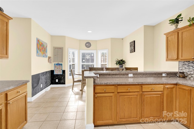 kitchen with backsplash, kitchen peninsula, and light tile patterned floors