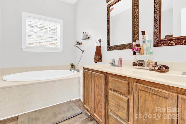 bathroom with tiled tub, vanity, and hardwood / wood-style floors