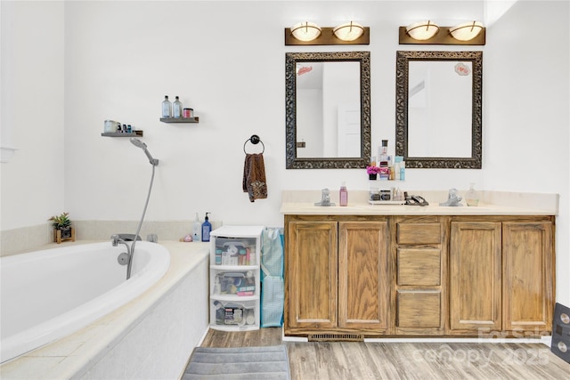 bathroom with a relaxing tiled tub, vanity, and hardwood / wood-style flooring