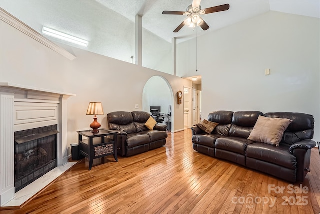 living room with high vaulted ceiling, a textured ceiling, ceiling fan, and light wood-type flooring