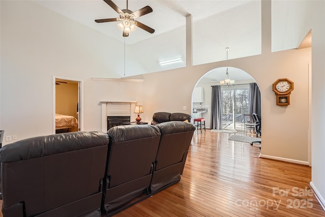 living room featuring ceiling fan with notable chandelier, high vaulted ceiling, and light hardwood / wood-style floors