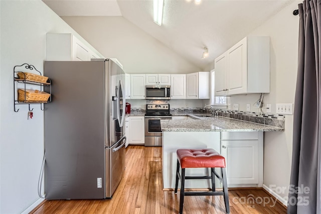 kitchen featuring white cabinets, lofted ceiling, stainless steel appliances, sink, and kitchen peninsula