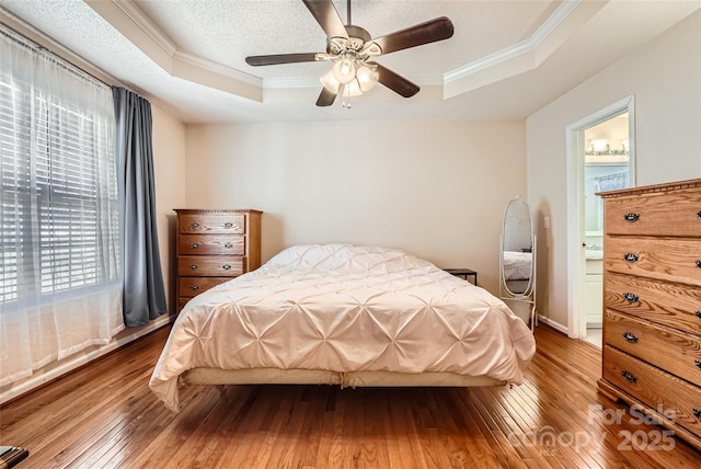 bedroom featuring ceiling fan, hardwood / wood-style floors, a tray ceiling, and ornamental molding