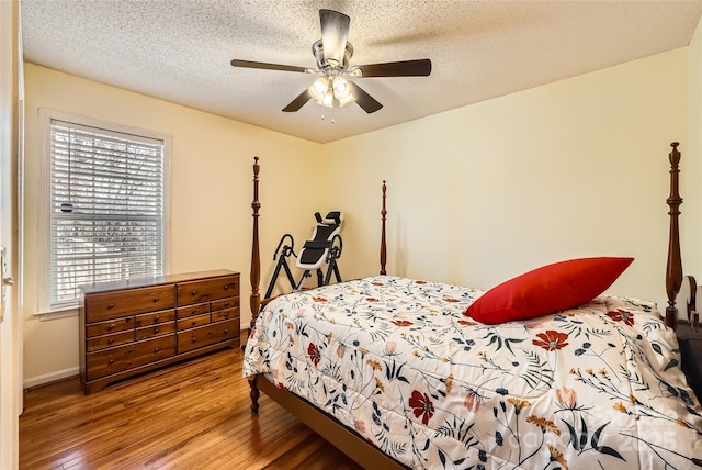 bedroom with ceiling fan, wood-type flooring, and a textured ceiling