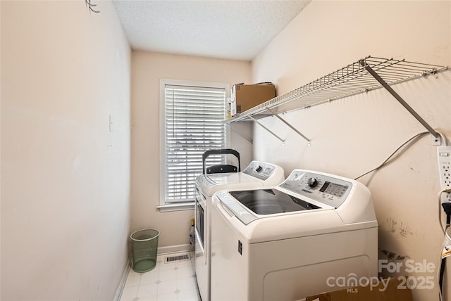 clothes washing area with separate washer and dryer and a textured ceiling