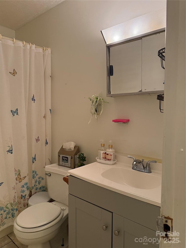 bathroom with toilet, tile patterned flooring, and vanity