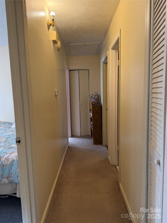 corridor featuring light colored carpet and a textured ceiling