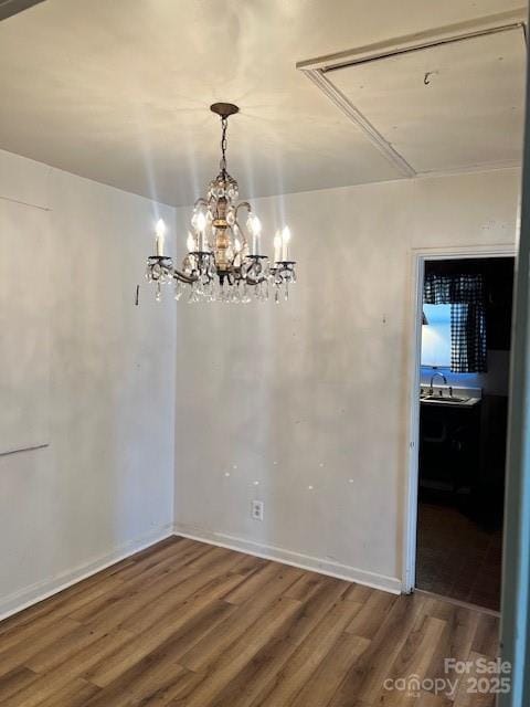 unfurnished dining area with sink, hardwood / wood-style floors, and an inviting chandelier