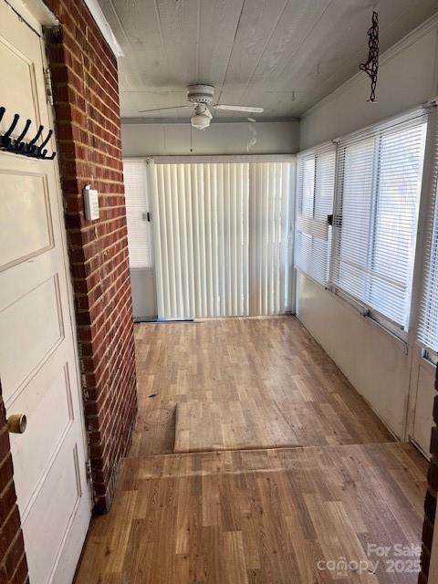 unfurnished sunroom featuring ceiling fan