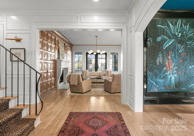 interior space with ornamental molding, a chandelier, and light hardwood / wood-style flooring