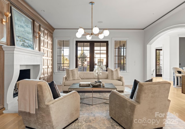 living room featuring ornamental molding, a chandelier, and light wood-type flooring