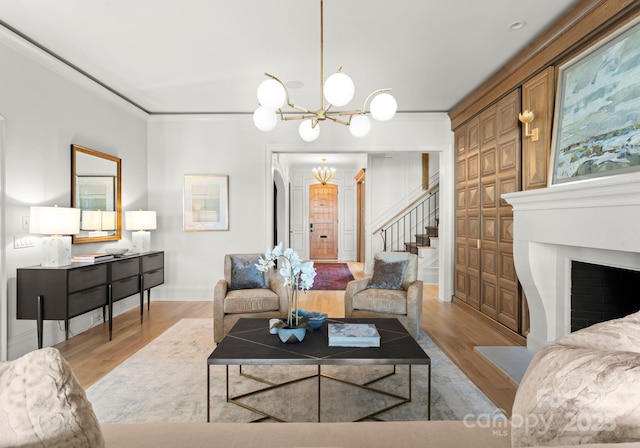 living room with ornamental molding, a chandelier, and light hardwood / wood-style flooring