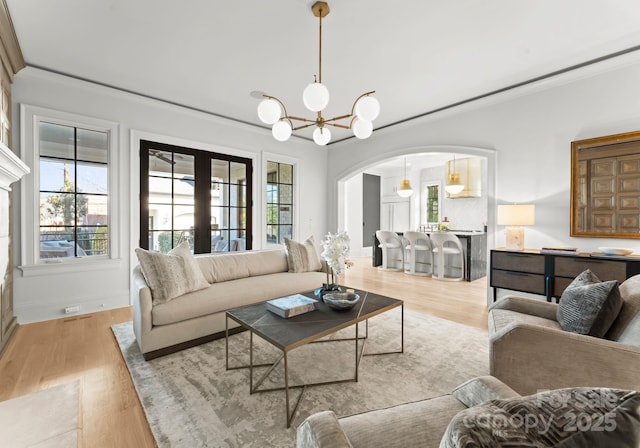 living room featuring crown molding, a notable chandelier, and light wood-type flooring