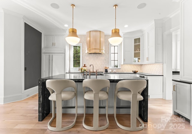 kitchen featuring paneled built in refrigerator, a center island, light hardwood / wood-style floors, white cabinets, and decorative light fixtures