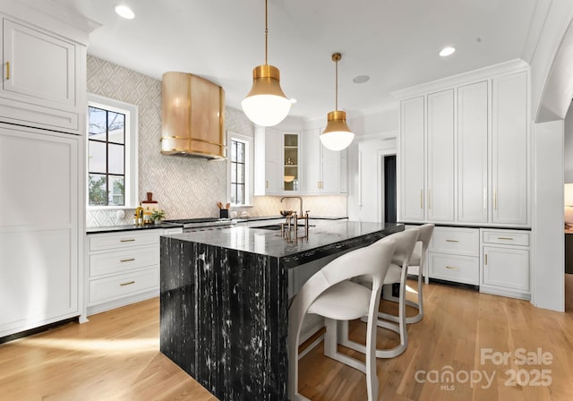 kitchen with dark stone counters, sink, a kitchen island, and white cabinets