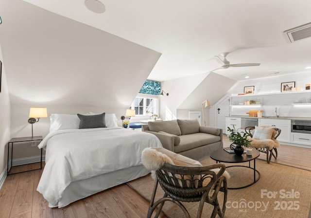 bedroom with vaulted ceiling, sink, and light wood-type flooring