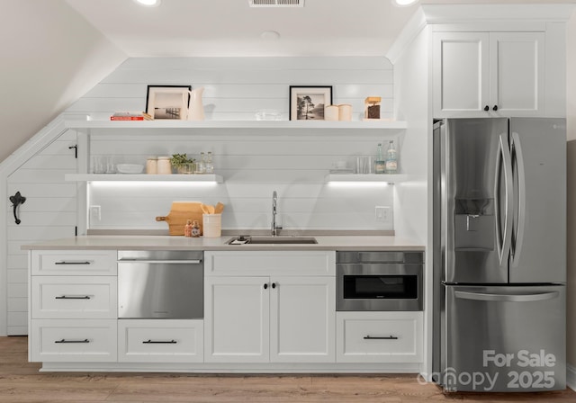 interior space featuring light wood-type flooring, appliances with stainless steel finishes, sink, and white cabinets