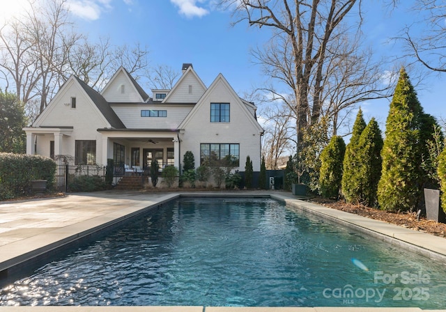 rear view of property with a fenced in pool, a patio, and ceiling fan