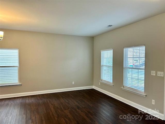 spare room featuring baseboards and dark wood finished floors