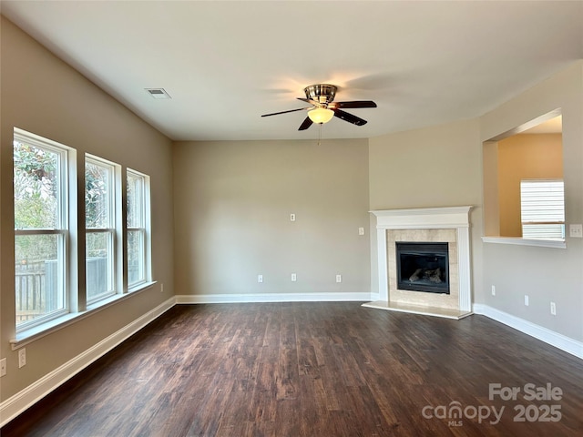 unfurnished living room featuring baseboards, visible vents, ceiling fan, dark wood-style flooring, and a fireplace