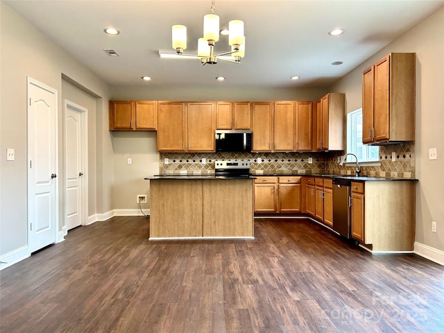 kitchen with stainless steel appliances, brown cabinetry, and dark countertops