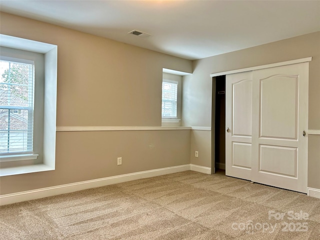 unfurnished bedroom featuring baseboards, visible vents, and light colored carpet