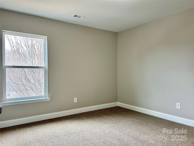 unfurnished room with carpet floors, visible vents, and baseboards