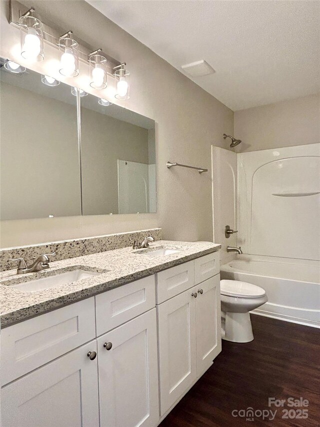 bathroom with washtub / shower combination, double vanity, a sink, and wood finished floors