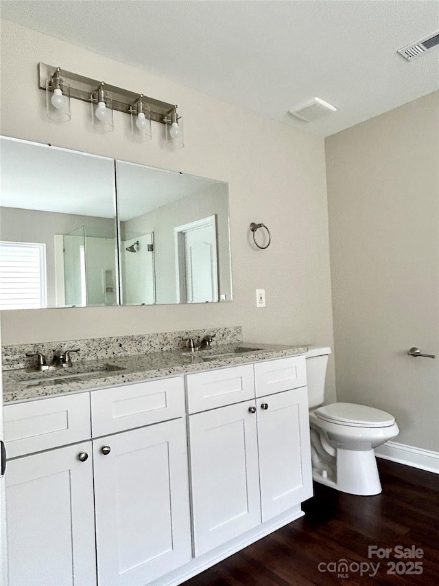 bathroom featuring visible vents, a sink, toilet, and double vanity