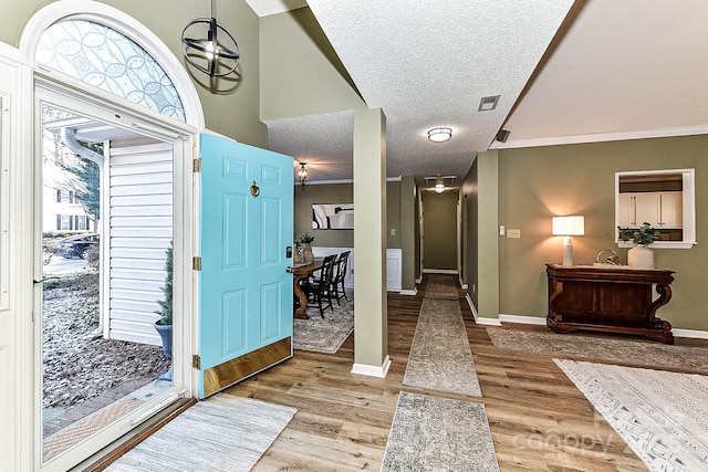 entryway with a textured ceiling, light hardwood / wood-style flooring, and ornamental molding