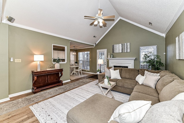 living room featuring ceiling fan, hardwood / wood-style floors, a textured ceiling, ornamental molding, and lofted ceiling